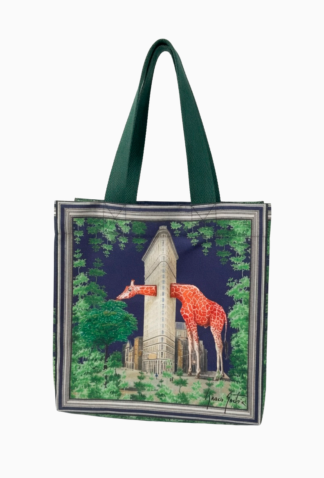 Bolso tote con asas verdes, estampado de jirafas junto al Flatiron Building rodeado de árboles sobre fondo azul
